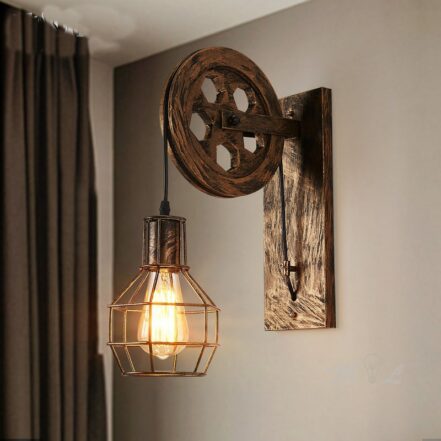 Lampe murale vintage composé d'une roue en bronze fixé sur un mur gris et avec un rideau gris