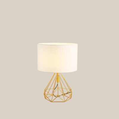 Une lampe de chevet au pied en métal doré, l'abat-jour en tissu blanc sur fond beige.