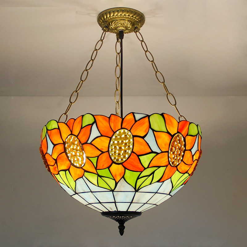 Lampe style Tiffany représentant des fleurs oranges, elle est supendue au plafond par des chainettes en métal