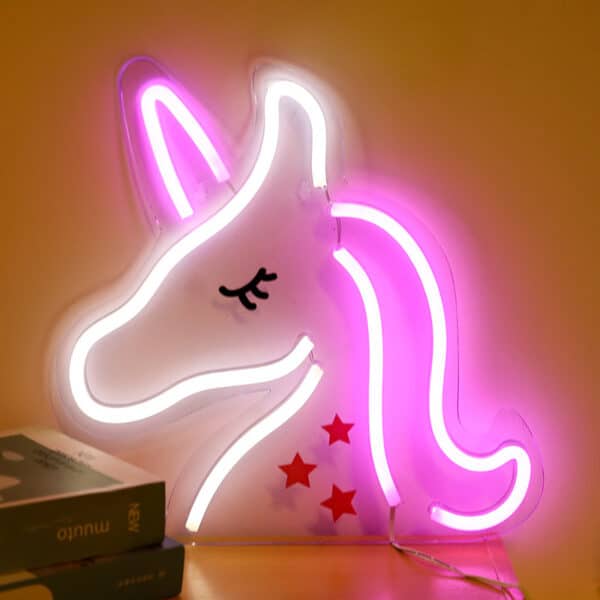lampe néon en forme de licorne blanche et rose de profil, la lampe est allumée dans la pénombre