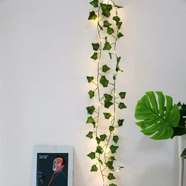 Guirlande lumineuse LED style feuilles de vignes pour décoration intérieure installée le long d'un mur blanc