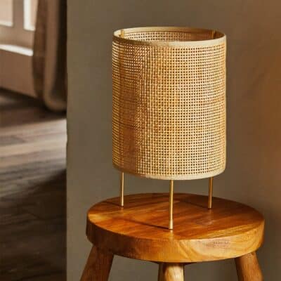 Lampe de bureau en rotin décorative présenté sur un tabouret en bois