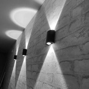 Lampe extérieure murale LED imperméable éclairage haut et bas présentée sur un mur gris extérieur