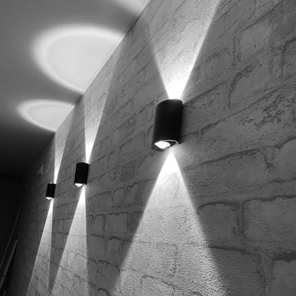 Lampe extérieure murale LED imperméable éclairage haut et bas présentée sur un mur gris extérieur