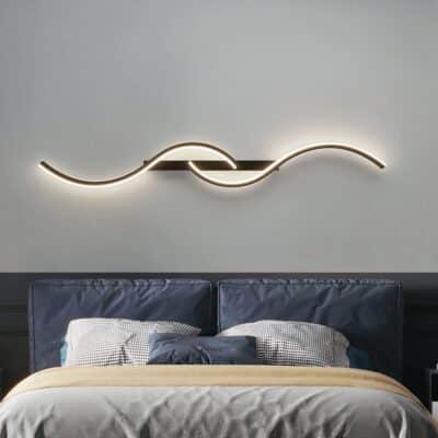 Lampe murale LED au design minimaliste moderne ondulation présentée installée au dessus d'un lit