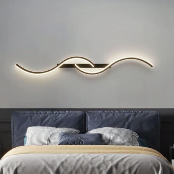 Lampe murale LED au design minimaliste moderne ondulation présentée installée au dessus d'un lit