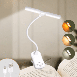 Lampe de lecture blanche à pince, accrochée à la page d'un livre. Sa tige est flexible. En bas à gauche un cercle avec les 2 embouts USB et sur le côté droit 3 cercle avec les différentes luminosités possible.