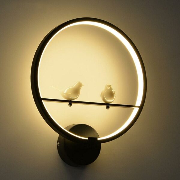 Lampe murale LED circulaire avec 2 oiseaux au centre présentée en noire et éclairée