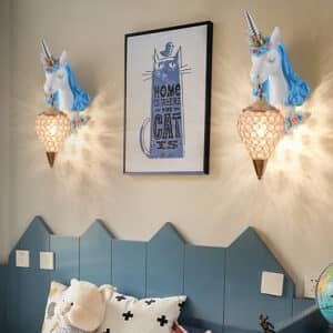 Lampe licorne applique murale LED bleue présentée installée de part et d'autre d'un lit d'enfant