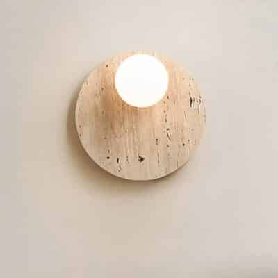 Lampe murale ronde design épuré présenté sur un mur beige
