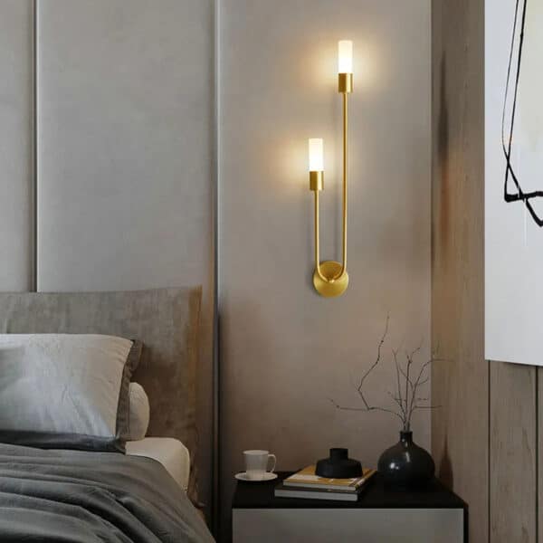 Lampe murale LED design épuré en laiton présentée installée dans une chambre
