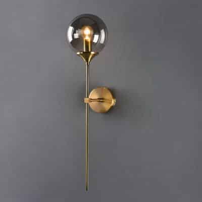 Lampe murale dorée design moderne présentée installée sur un mur gris