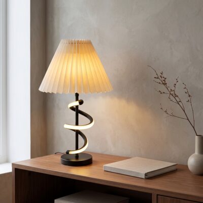 Une lampe ondulée moderne aux trois couleurs réglables posée sur une table en bois, avec un abat-jour blanc plissé et une lumière chaude, dans une pièce calme.