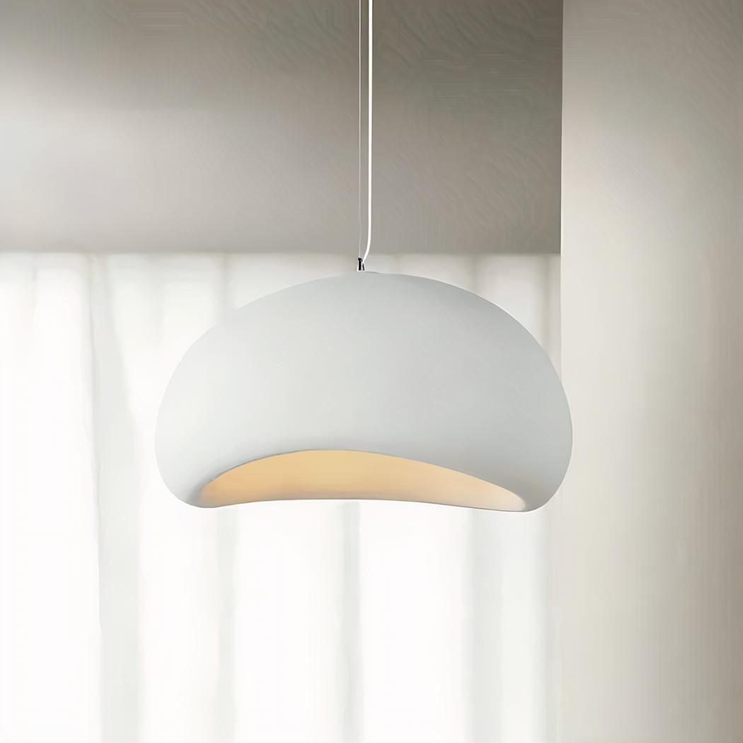 Une suspension Wabi Sabi en plâtre effet pierre minimaliste blanche, suspendue au plafond et diffusant une lumière douce dans une pièce claire.