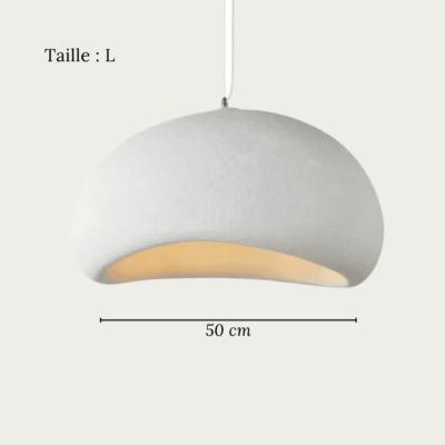 Une suspension Wabi Sabi en plâtre effet pierre minimaliste blanche, suspendue au plafond et diffusant une lumière douce dans une pièce claire.
